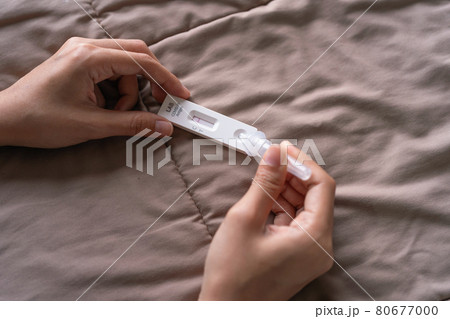 Hand holds a test cartridge at home. COVID-19 Ag rapid self test kits on bed at home in quarantine. Antigen or Antibody test. Virus disease healthcare check. Coronavirus outbreak. 80677000