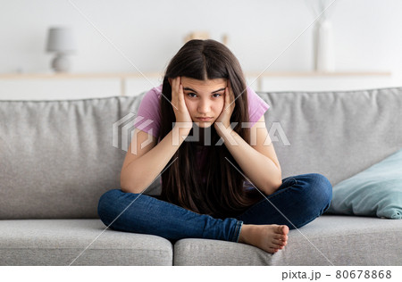 Upset Indian teenage girl sitting on couch, feeling bored, suffering from lack of communication, being trapped at home 80678868