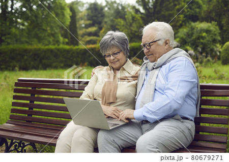 Cheerful senior couple using laptop at park Cheerful senior couple using laptop at park 80679271
