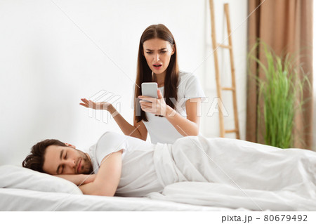 Shocked Woman Reading Cheating Husband's Messages On Cellphone In Bedroom 80679492