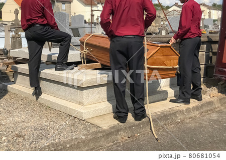 Porters lower the coffin into the grave 80681054
