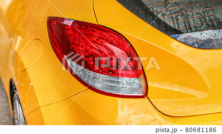 Rear light of yellow car covered with water when washed in carwash. Rear light of yellow car covered with water when washed in carwash. 80681186