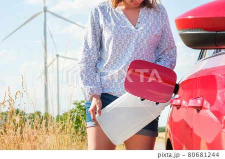 Woman filling a diesel exhaust fluid or petrol on the background of wind turbines. Green energy against environmental pollution. Woman filling a diesel exhaust fluid or petrol on the background of wind turbines. Green energy against environmental pollution. 80681244