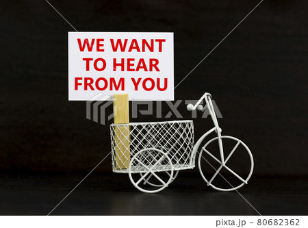 Support symbol. Wooden clothespin with white sheet of paper. Text 'we want to hear from you'. Miniature bicycle model. Beautiful black background. Business and support concept, copy space. Support symbol. Wooden clothespin with white sheet of paper. Text 'we want to hear from you'. Miniature bicycle model. Beautiful black background. Business and support concept, copy space. 80682362