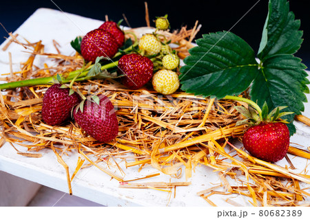 Food dark photography Strawberries, strawberry leaves and straw on wooden pad and dramatic dark background. 80682389