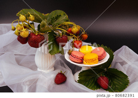 Food dark photography Strawberries and colorful macarons on the white scarf and dramatic dark background. 80682391