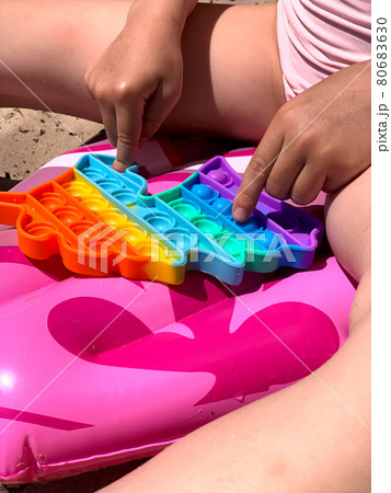Little girl plays with cotton on the beach. A modern toy for toddlers. Antistress toy Little girl plays with cotton on the beach. A modern toy for toddlers. Antistress toy 80683630
