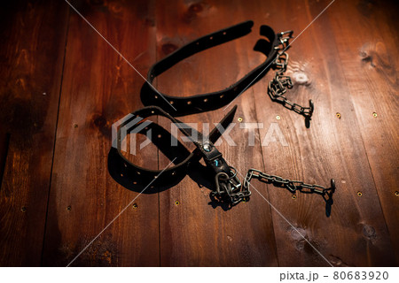 Leather handcuffs for role-playing games lie on a wooden background. bdsm toys for dominantrix. 80683920