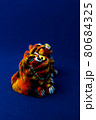 青をバックグラウンドにしたオレンジ色のシーサー 80684325