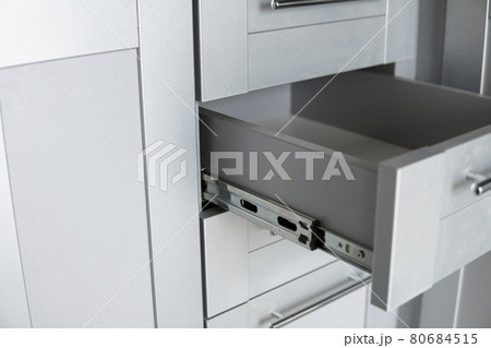 Stainless telescopic bayonet drawer slide guides, installed on a kitchen cabinet from gray chipboard. Accessories for carpentry used in the construction of furniture. Custom kitchen installation. Stainless telescopic bayonet drawer slide guides, installed on a kitchen cabinet from gray chipboard. Accessories for carpentry used in the construction of furniture. Custom kitchen installation. 80684515