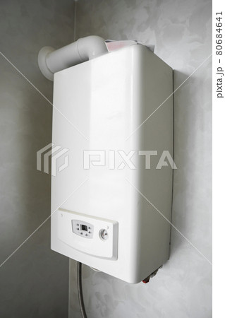 White modern home gas boiler mounted on a grey wall on a kitchen. Water heater. Water heating, ecology. 80684641