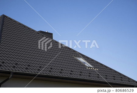 Brown corrugated metal profile roof installed on a modern house. The roof of corrugated sheet. Roofing of metal profile wavy shape. Modern roof made of metal. Metal roofing. 80686529