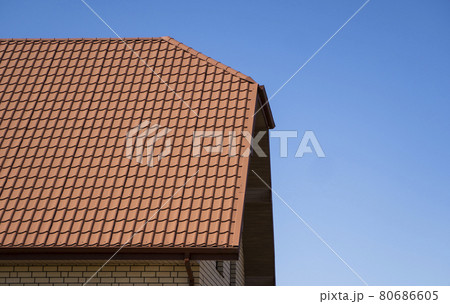 Red corrugated metal profile roof installed on a modern house. The roof of corrugated sheet. Roofing of metal profile wavy shape. Modern roof made of metal. Metal roofing. 80686605