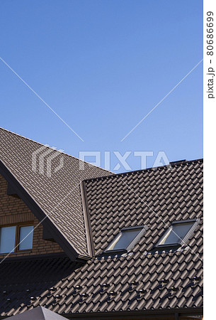 Brown corrugated metal profile roof installed on a modern house. The roof of corrugated sheet. Roofing of metal profile wavy shape. Modern roof made of metal. Metal roofing. 80686699