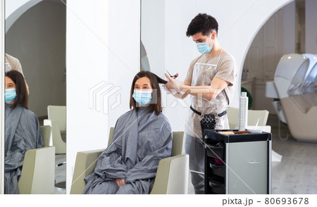 Woman client in mask during cuts hair at beauty salon Woman client in mask during cuts hair at beauty salon 80693678