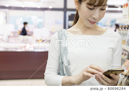 スーパーでスマホの買い物リストを見て商品を探す女性買い物客 80696284
