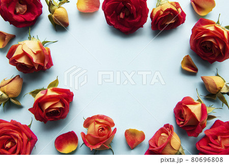 Flowers composition. Frame made of red roses and leaves on blue background Flowers composition. Frame made of red roses and leaves on blue background 80696808