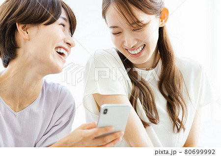スマホを見ながら歓談する2人の女性 80699992
