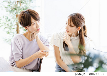 後ろの席の同僚と話をする2人のビジネスウーマン 80699997