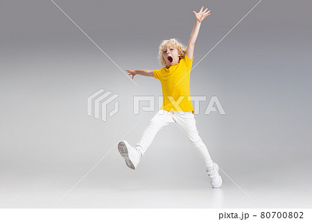 Cute little curly preschool boy having fun, playing isolated over light studio background. 80700802