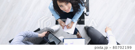 Business partners are sitting at table smiling and looking up Business partners are sitting at table smiling and looking up 80702199