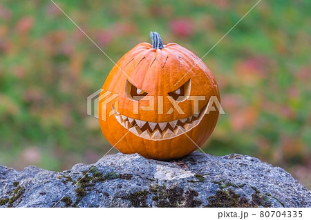 Scary smiling face halloween pumpkin on a stone 80704335