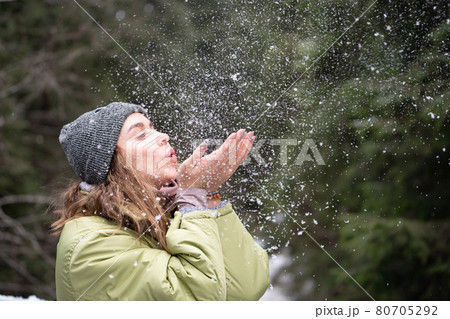 Woman Blowing Snow Outdoor on Winter background. Happiness and joy concept Woman Blowing Snow Outdoor on Winter background. Happiness and joy concept 80705292