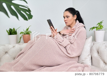 Surprised emotional middle-aged woman using smartphone for video call 80706779