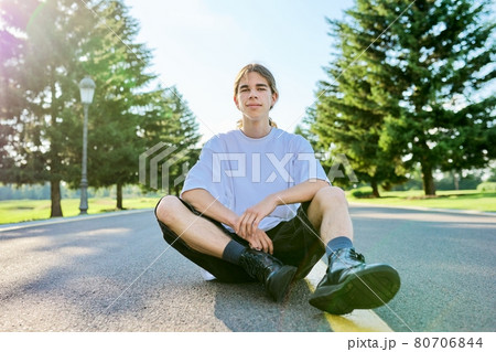 Fashion portrait of hipster teenager guy sitting on the road. Fashion portrait of hipster teenager guy sitting on the road. 80706844