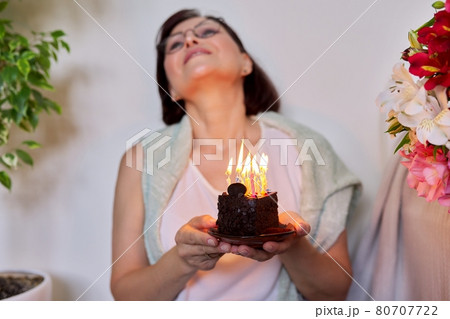 Middle-aged women with small birthday cake with candles 80707722