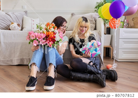 Mom congratulating daughter with bouquet of flowers and surprise gift box Mom congratulating daughter with bouquet of flowers and surprise gift box 80707812