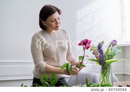 Mature woman at home with spring flowers Mature woman at home with spring flowers 80708088