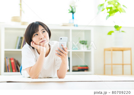 リビングでくつろぎながらスマホを操作する女性 リビングでくつろぎながらスマホを操作する女性 80709220