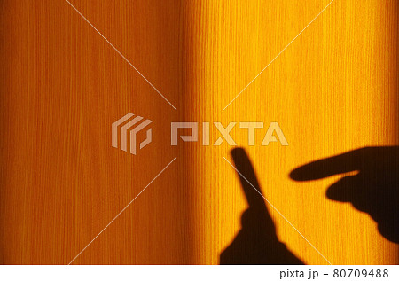 部屋の窓から西日が差してスマホを持つ手と操作する手の影が奥の襖に映る情景 80709488