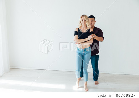 a man and a woman dance bachata to music in a white room a man and a woman dance bachata to music in a white room 80709827