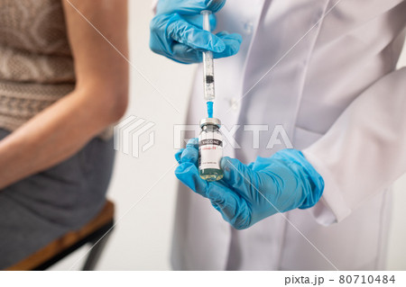 Doctor prepares a syringe with coronavirus vaccine for a patient. 80710484