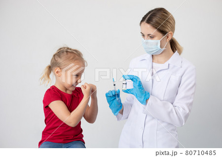 A child defends himself against a doctor with a covid vaccine and a syringe in his hands. 80710485