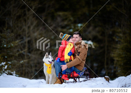 A father with a beautiful daughter and a husky dog are walking in the winter forest. A father with a beautiful daughter and a husky dog are walking in the winter forest. 80710552