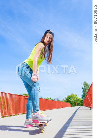 Teen girl skater riding skateboard on street. Teen girl skater riding skateboard on street. 80710925