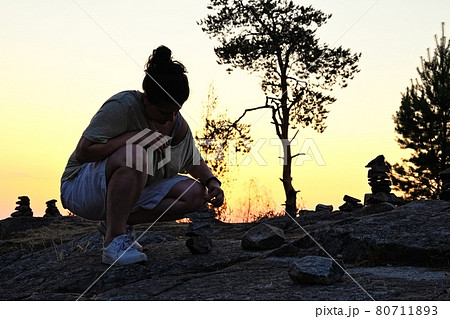 Woman make little stone pyramids in Karelija 80711893