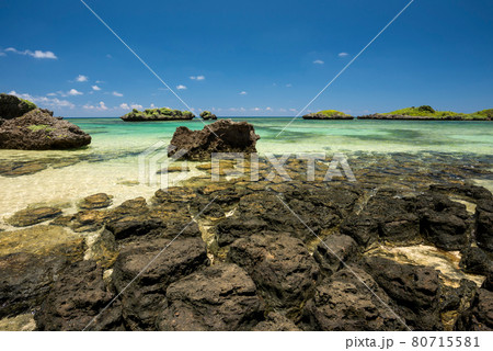 Stunning coastal rocks formation, emerald green sea, blue sky, green islets in the background, blue sky. Iriomote Island. Stunning coastal rocks formation, emerald green sea, blue sky, green islets in the background, blue sky. Iriomote Island. 80715581