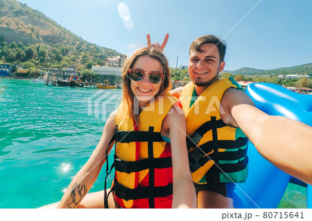 happy man and girl take a selfie riding on sea on banana boat 80715641