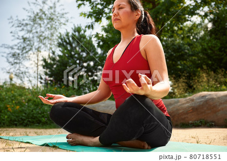 Adult asian woman doing yoga in nature, doing stretching and flexibility exercises, yoga class for adult women 80718551