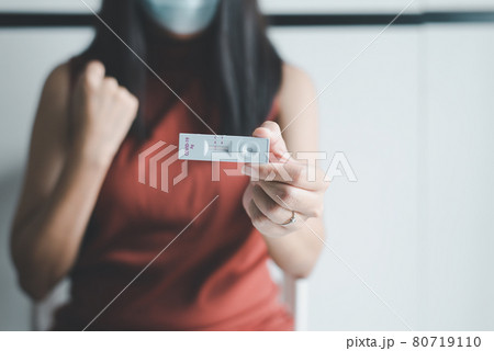Patient woman showing result a covid-19 self test rapid antigen testing kit at home Patient woman showing result a covid-19 self test rapid antigen testing kit at home 80719110
