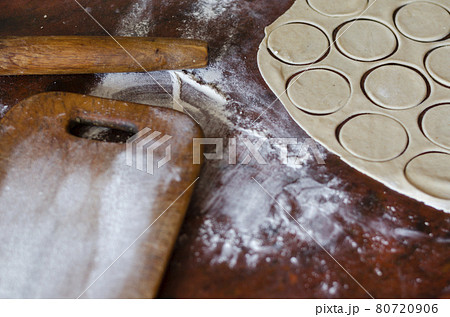 Thinly rolled dough for meat dumplings on the kitchen table. Thinly rolled dough for meat dumplings on the kitchen table. 80720906