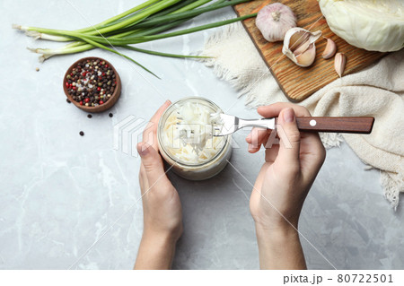 Woman eating fermented cabbage at light grey marble table, top view Woman eating fermented cabbage at light grey marble table, top view 80722501