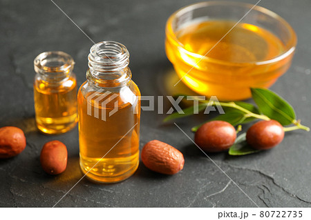 Jojoba oil and seeds on dark grey table Jojoba oil and seeds on dark grey table 80722735