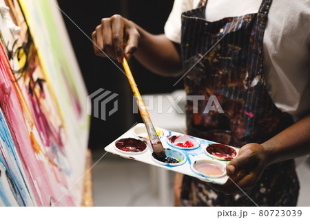 African american male painter at work painting on canvas in art studio African american male painter at work painting on canvas in art studio 80723039