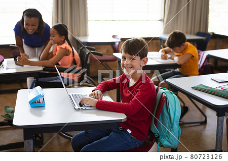 Portrait of caucasian boy with laptop smiling while sitting on his desk at elementary school Portrait of caucasian boy with laptop smiling while sitting on his desk at elementary school 80723126