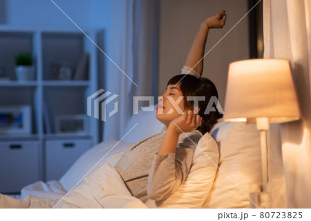 tired asian woman stretching in bed at night tired asian woman stretching in bed at night 80723825